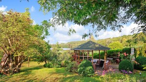 A gazebo with a tiled roof surrounded by lush greenery and flowering plants. - Ferienwohnung Wokuhl-Dabelow (Wokuhl-Dabelow)