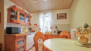 A kitchen with wooden cabinets, a microwave, a stove, and a dining table with chairs. - Ferienwohnung Wokuhl-Dabelow (Wokuhl-Dabelow)