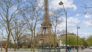 The Eiffel Tower surrounded by leafless trees and a clear sky. - Studio St Dominique - Invalides - B'Your Home (Paris)