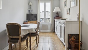 A dining area with a table, chairs, a television, and a cabinet. - Studio St Dominique - Invalides - B'Your Home (Paris)