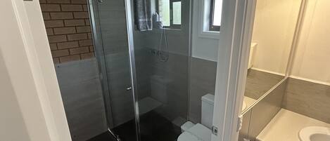 Une salle de bain avec une douche à parois de verre, des toilettes et un lavabo.