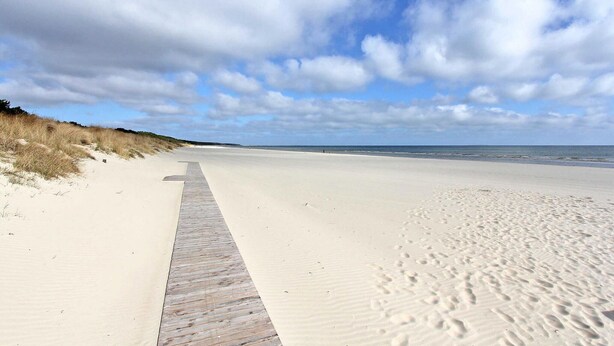 A sandy beach with a wooden boardwalk leading to the water. - Ferienwohnung Karlshagen (Karlshagen (Ostseebad))
