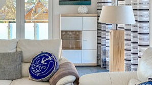 A living room with a sofa, a coffee table, a lamp, and a cabinet. - Ferienwohnung Karlshagen (Karlshagen (Ostseebad))