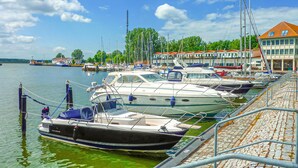 A marina with several boats docked, a stone-paved walkway, and buildings in the background. - Ferienwohnung Karlshagen (Karlshagen (Ostseebad))
