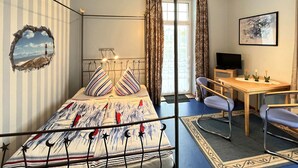 Un dormitorio con una cama, un escritorio, una silla, un televisor y una ventana con cortinas.