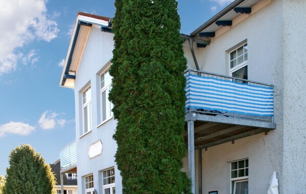 En byggnad med flera våningar och en balkong med ett randigt solskydd.