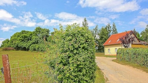 A rural setting with a dirt path leading to a yellow house with a red roof. - Ferienwohnung Walow Strietfeld (Walow OT Strietfeld)