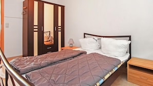 A bedroom with a bed, a wooden wardrobe, a nightstand, and a small wooden dresser. - Ferienwohnung Walow Strietfeld (Walow OT Strietfeld)