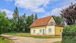 A single-story house with a sloped roof, a fenced yard, and a gravel driveway. - Ferienwohnung Walow Strietfeld (Walow OT Strietfeld)