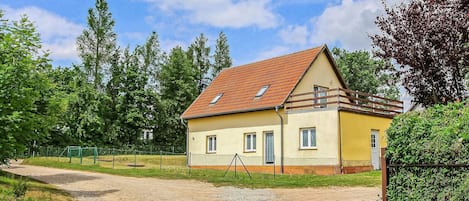 Ein eingeschossiges Haus mit geneigtem Dach, einem umzäunten Garten und einer Schotterauffahrt.