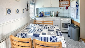 Een kleine keuken met een eettafel, stoelen en essentiële apparaten.