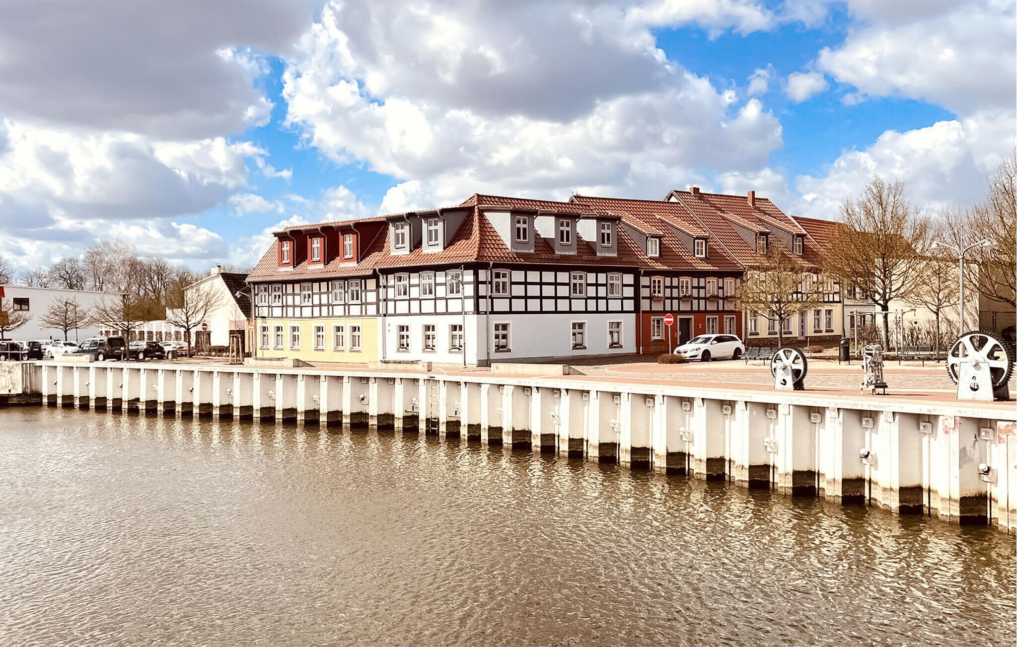 Ein traditionelles Fachwerkhäuschen mit rotem Ziegeldach, gelegen an einem ruhigen Fluss.