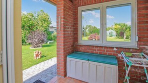 Ein Zimmer mit Backsteinwand, einem Fenster mit Gartenblick, einer Bank und einem Wäscheständer.