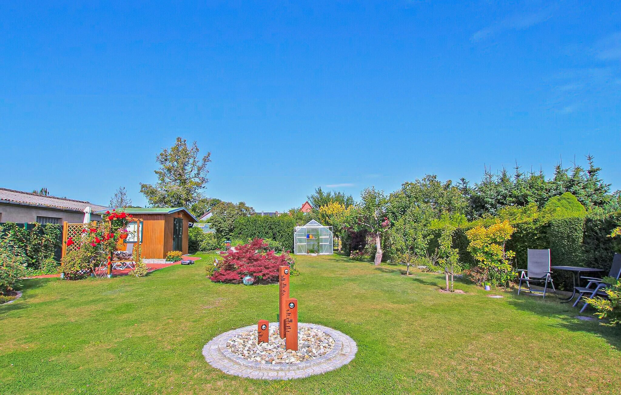 A well-maintained garden with a circular stone feature, a wooden shed, and a greenhouse.