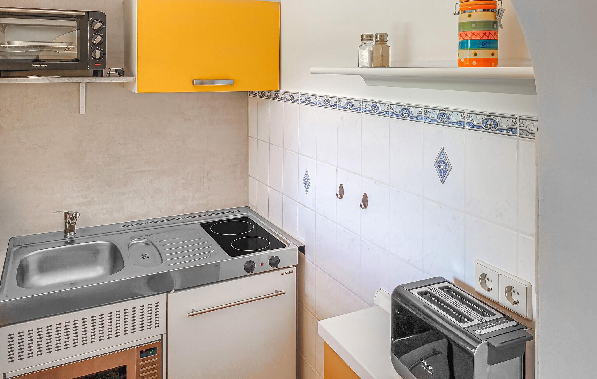 Cocina compacta con estufa, fregadero y tostadora.