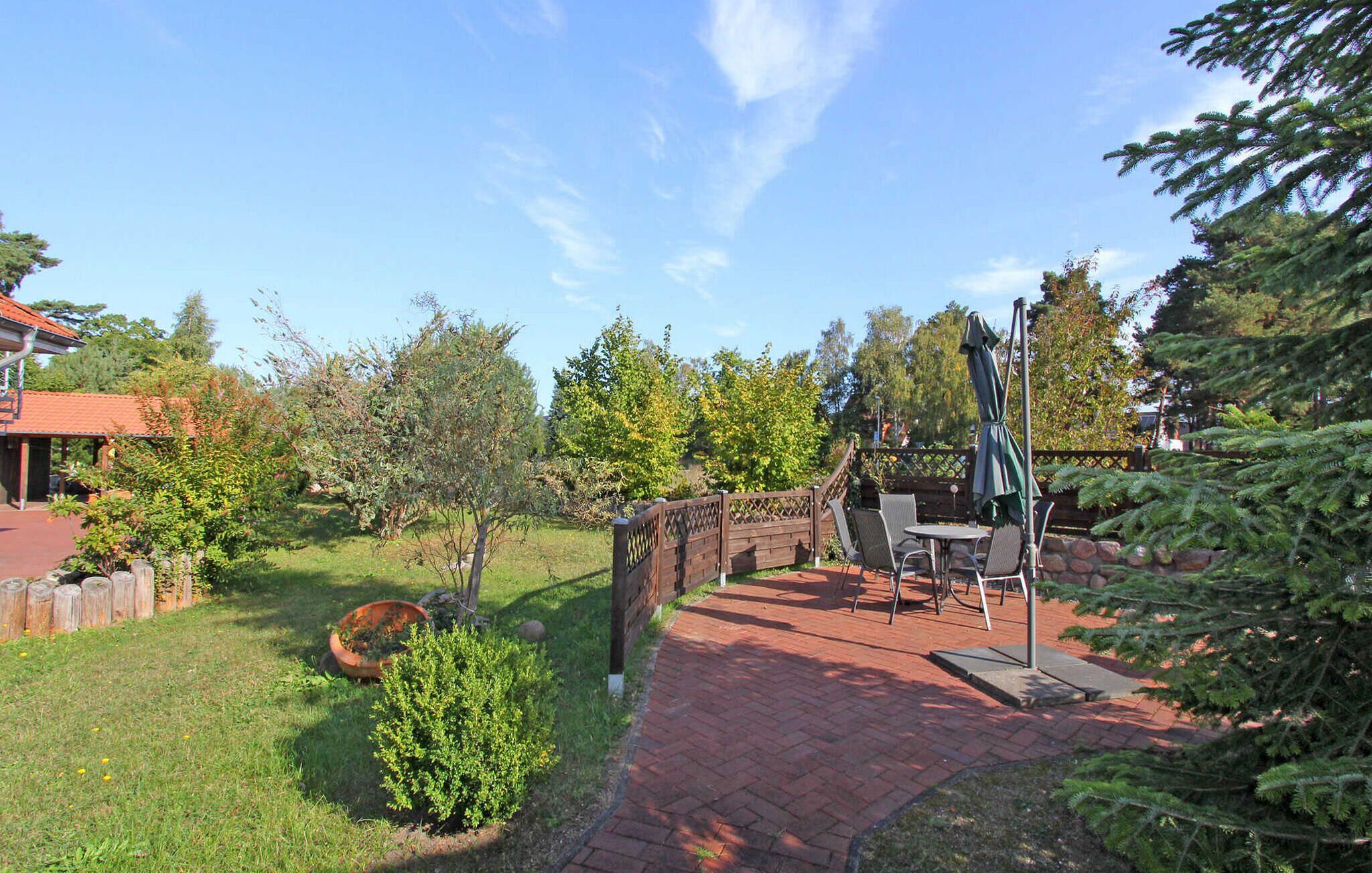 Un'area patio con vialetto in mattoni, arredi da esterno e recinzione in legno.