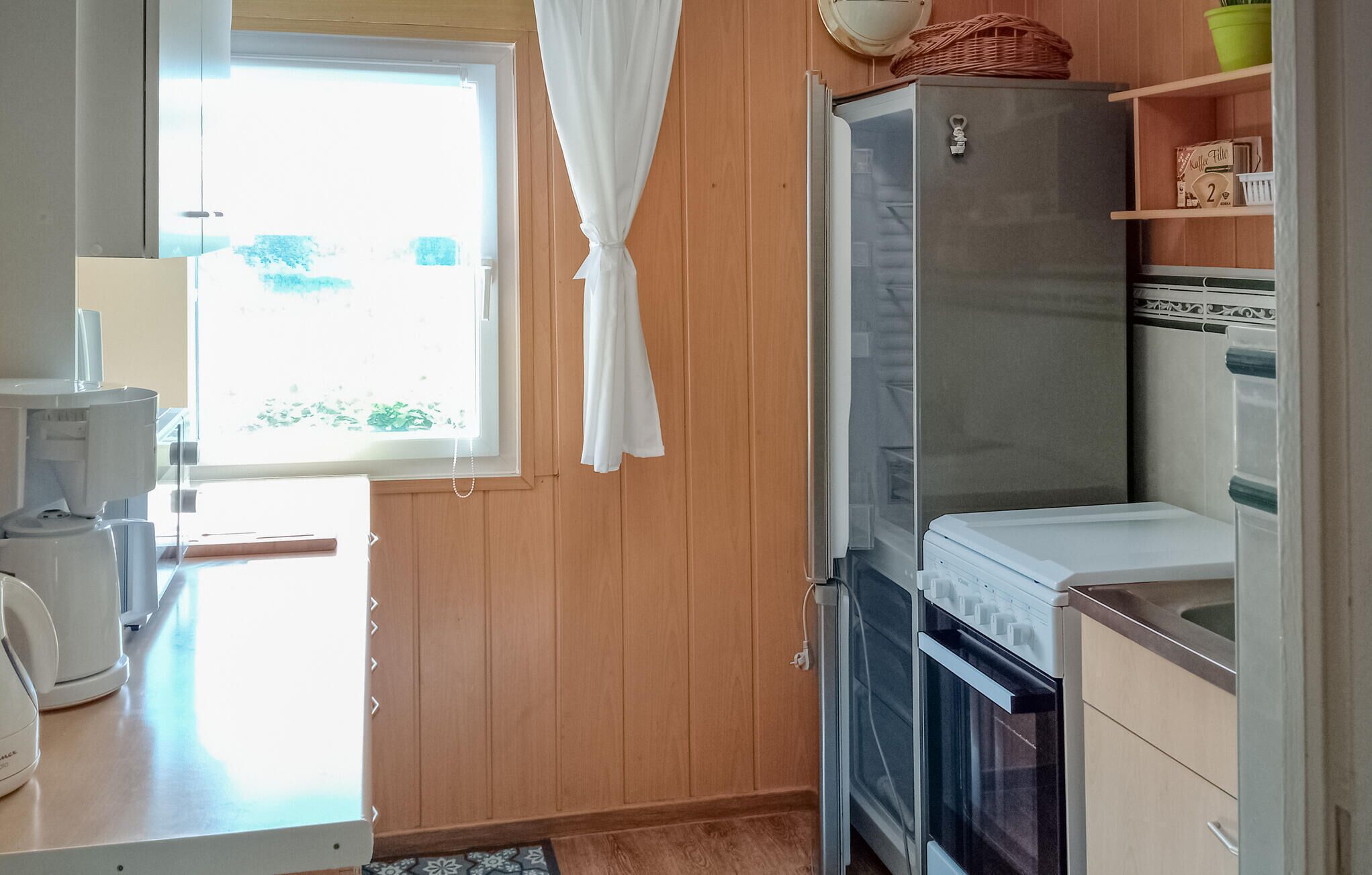 Una cocina compacta con refrigerador, horno y cafetera.
