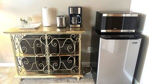 Une petite cuisine équipée d’un réfrigérateur, d’un four à micro-ondes, d’une machine à café et d’un grille-pain, le tout installé sur un meuble en bois.