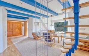 A spacious living area with a high ceiling, wooden flooring, and a large window providing a view of the outdoors. - Ferienwohnung Pruchten (Pruchten)