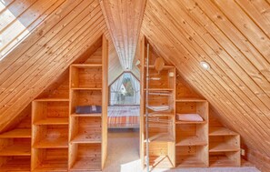 A wooden attic room with sloped ceilings and built-in wooden shelves. - Ferienwohnung Pruchten (Pruchten)