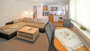 Un espace de vie compact comprenant un canapé, une petite table, un coin cuisine et une fenêtre avec des rideaux.