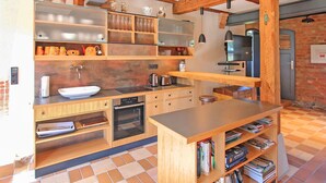 A modern kitchen with wooden cabinetry, a built-in oven, and a bookshelf filled with books.