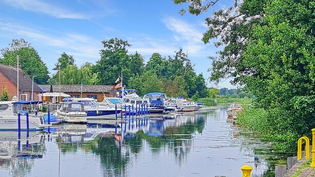 Un canal bordé de bateaux à quai, entouré de verdure et de bâtiments.