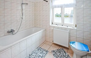 A bathroom with a bathtub, a toilet, and a window. - Ferienwohnung Eggesin (Eggesin)