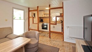 A compact living space with a kitchenette, a sofa, a dining table, and a television. - Cozy home in Kummerow with sauna (Kummerow)