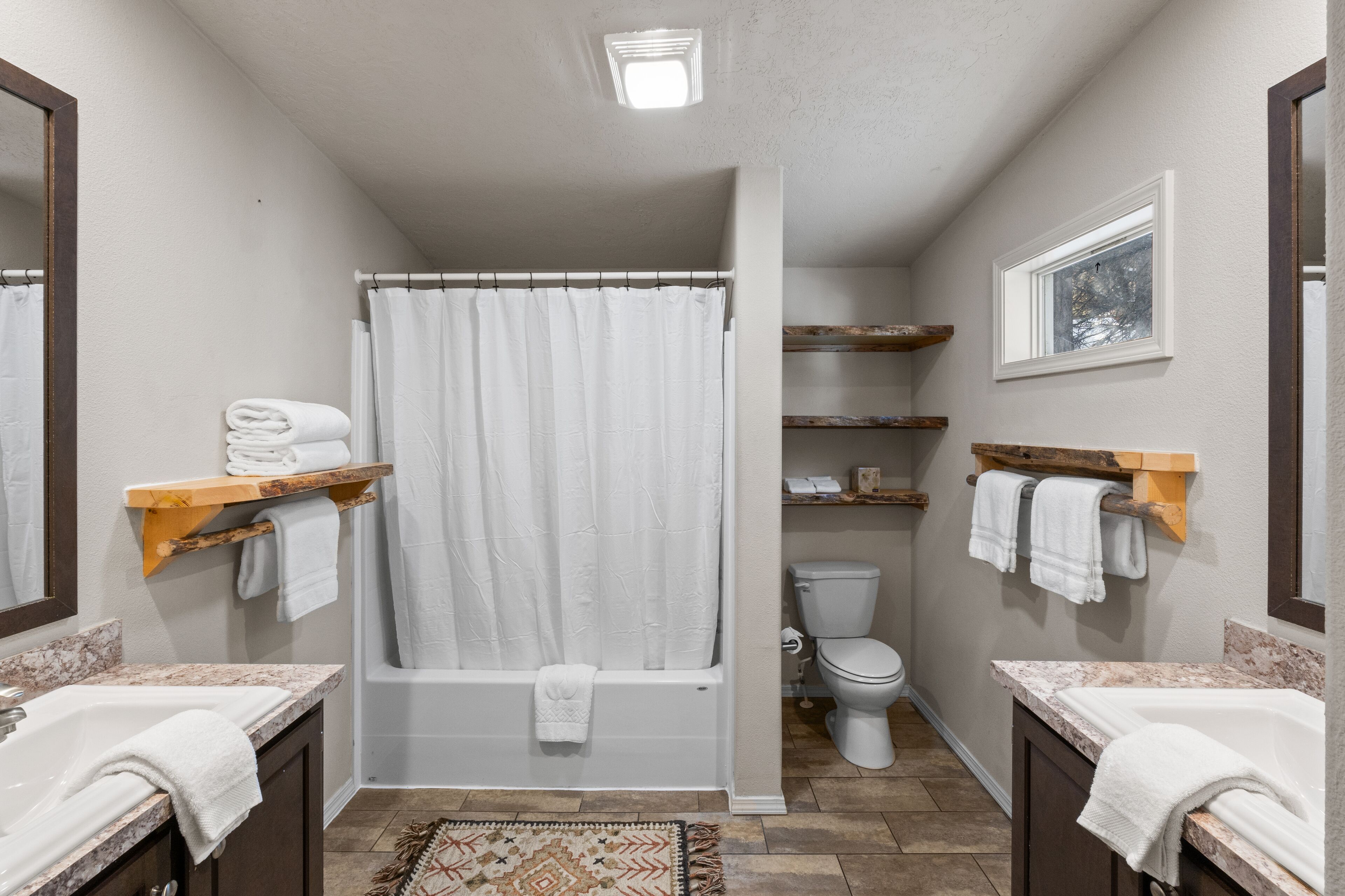 A bathroom with a bathtub, toilet, and two sinks with towel racks.