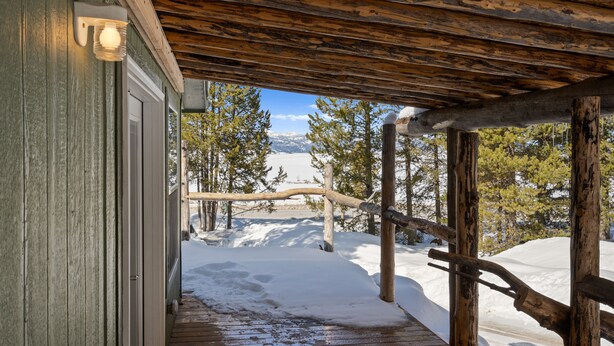 A wooden deck leading to a building with a snow-covered landscape and mountains in the background. - Dreamcatcher (West Yellowstone)