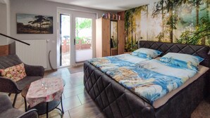 Une chambre à coucher avec un lit, un canapé, une petite table et un tableau accroché au mur.