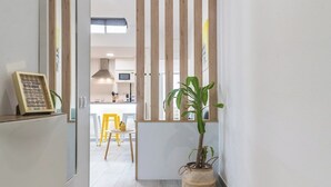 Un pasillo estrecho con un separador de listones de madera, una planta en maceta y un mostrador de recepción con un letrero.