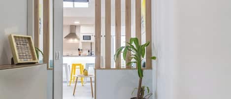 A narrow hallway with a wooden slat partition, a potted plant, and a reception desk with a sign.