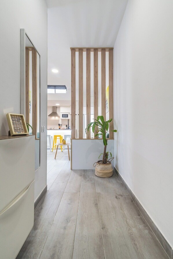 A narrow hallway with a wooden slat partition, a potted plant, and a reception desk with a sign.