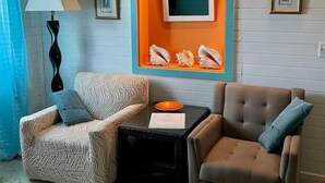 A room with two armchairs, a small table with a lamp, and a wall display with shells. - 2bdrm, Water deck views Bag Drop
 (Culebra)