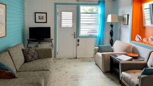 A living room with a television, two sofas, a coffee table, and a door with a window. - 2bdrm, Water deck views Bag Drop
 (Culebra)