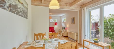 A dining area with wooden furniture, a table set for four, and a view of the outdoors through large windows.
