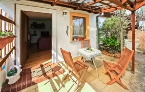 Une terrasse avec une table et des chaises, un petit jardin et une vue sur l’intérieur.