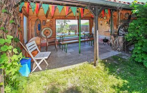 Une structure rustique en bois dotée d’un patio couvert, d’un banc et d’une table.