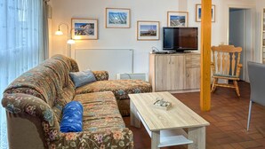 Una sala de estar con sofá, una mesa de centro, un televisor y un mueble de madera.