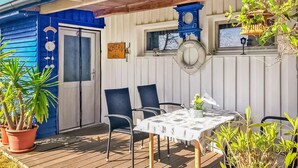 Un área de estar al aire libre techada, con una mesa, sillas, un reloj y un cartel de bienvenida.