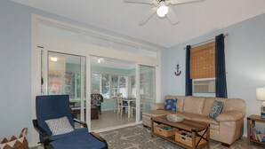 A living room with a blue armchair, a beige sofa, a wooden coffee table, and a ceiling fan. - Beautiful Summer village cottage close to the Ocean! (Wells)