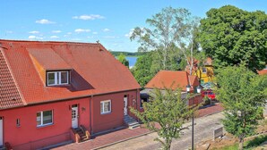 Un bâtiment rouge avec un toit en tuiles, une petite fenêtre et une porte.