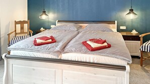 Un lit double avec deux serviettes rouges, une tête de lit en bois et un mur bleu.