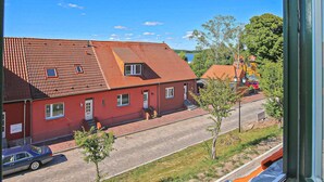 Un bâtiment rouge avec un toit en tuiles, une rue pavée et une voiture garée.