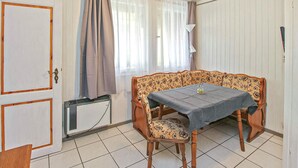 Une pièce comprenant une table à manger, une chaise, un radiateur, une porte et une fenêtre avec des rideaux.