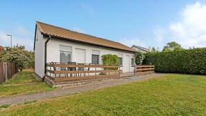Een gelijkvloers huis met een pannendak, een veranda met houten leuningen en een kleine tuin.