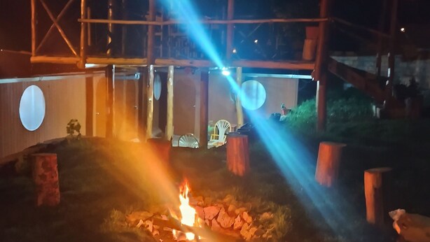A nighttime outdoor area with a fire pit, wooden structures, and a circular light fixture. - the wooden house choquequirao (San Pedro de Cachora)