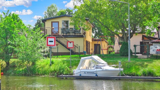 Ein Boot liegt an einem Kanal, im Hintergrund ein Haus.